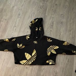 This is an Adidas cropped hoodie, black and gold